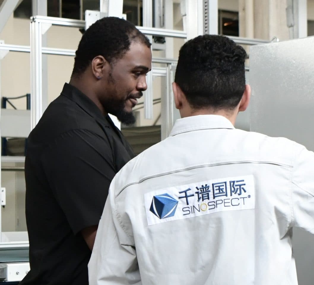 Contrôle témoin côté client sur le site fournisseur en Chine — deux inspecteurs examinant un équipement sur place.