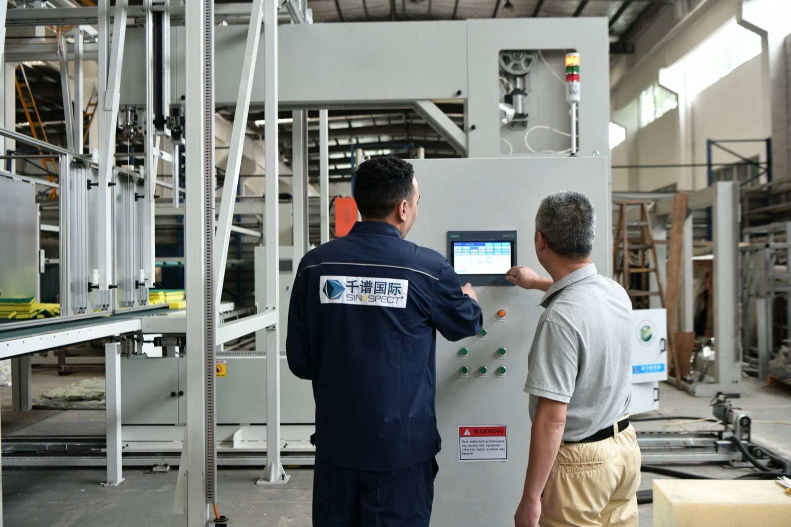 Inspecteur Sinospect et ingénieur d’usine au pupitre de commande d’une machine lors d’une réception usine