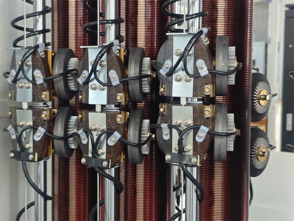 Gros plan sur les enroulements d'un transformateur moyenne tension et les contacts du régleur en charge lors d'une inspection en usine — bobinages cuivre, noyaux feuilletés et matériel de sélection visible.