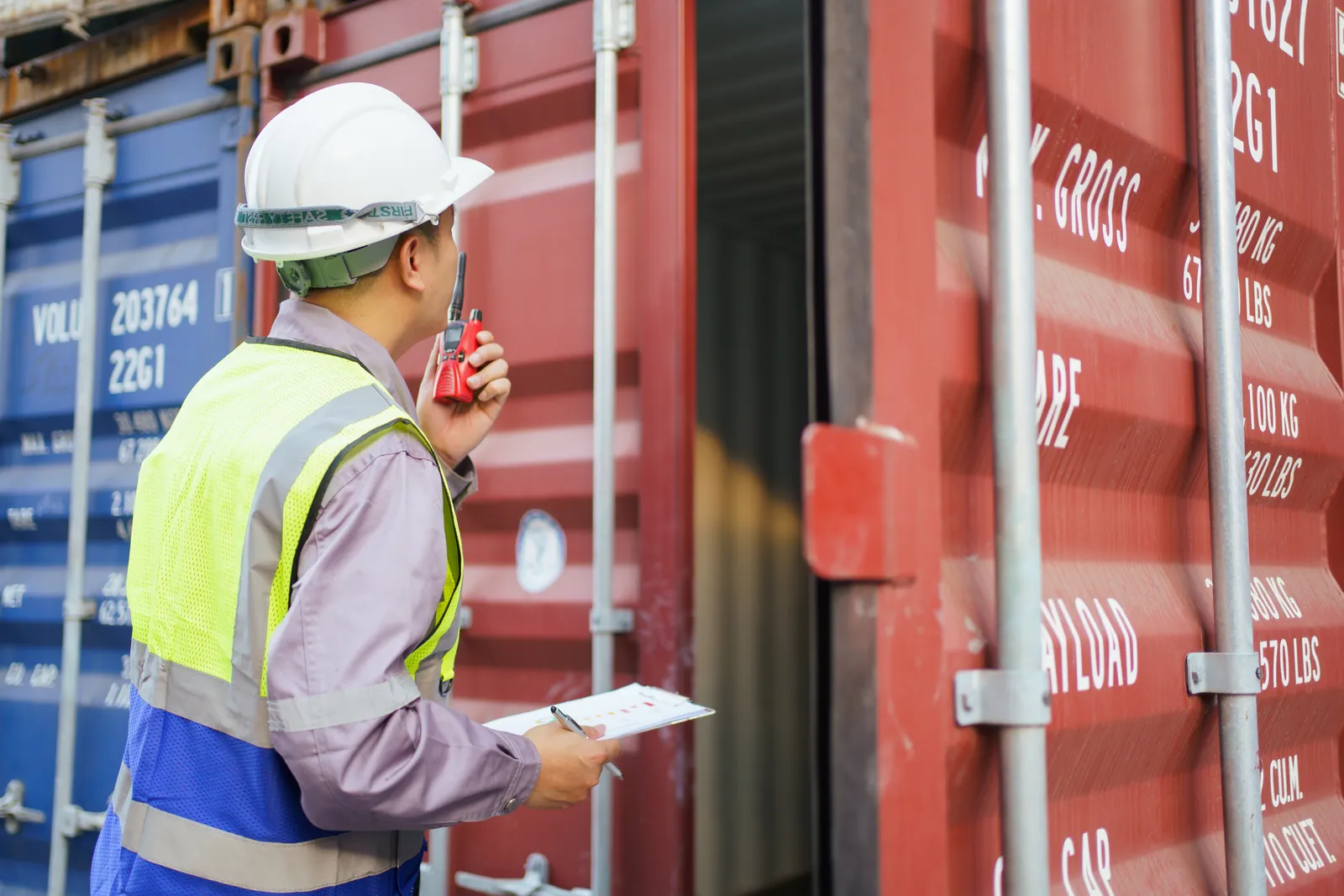 Inspector supervising container loading at a Chinese export yard — cargo checked against the packing list before the container is sealed