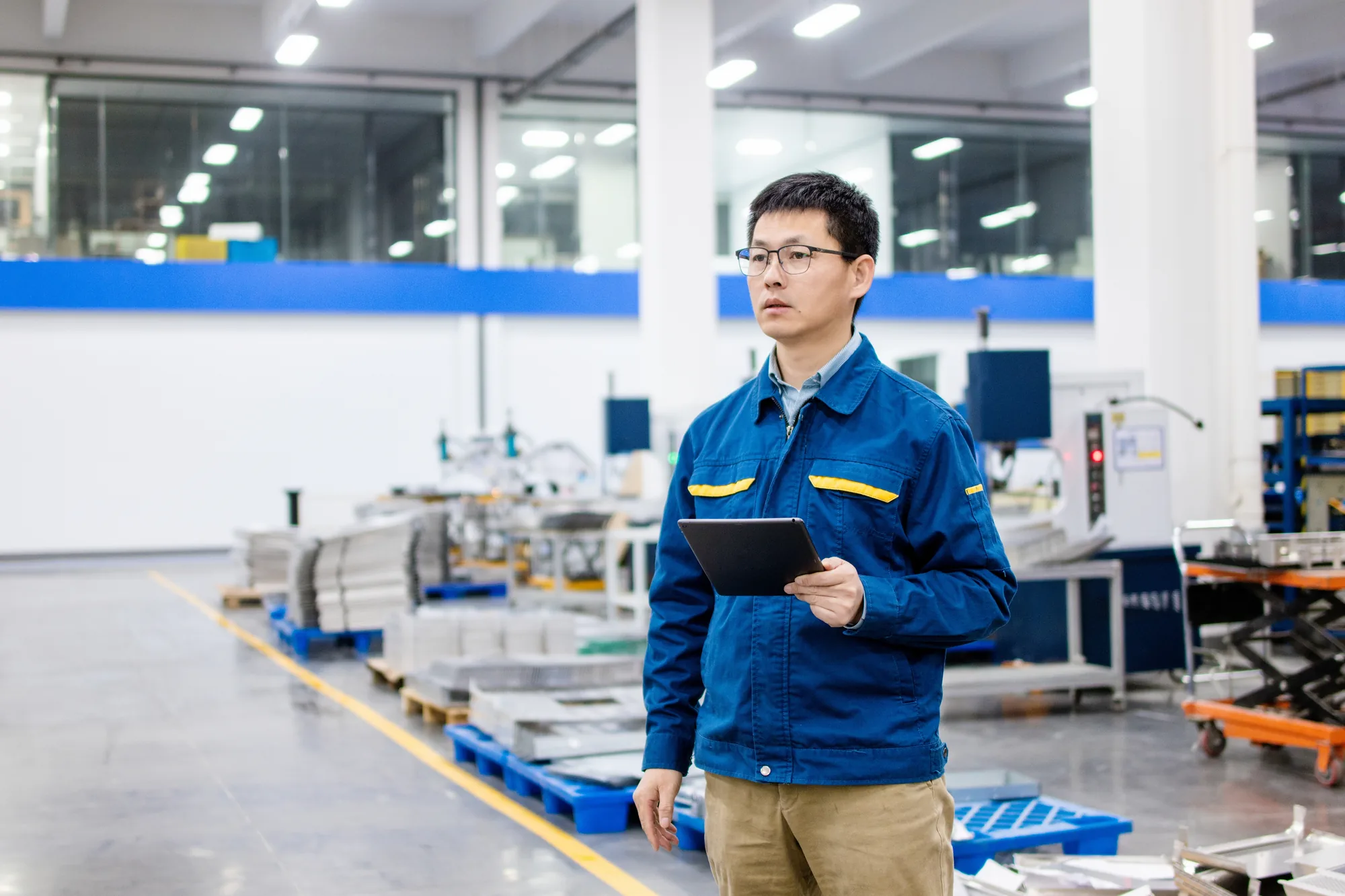 Inspection coordinator walking a Chinese manufacturing floor with a tablet for in-process verification