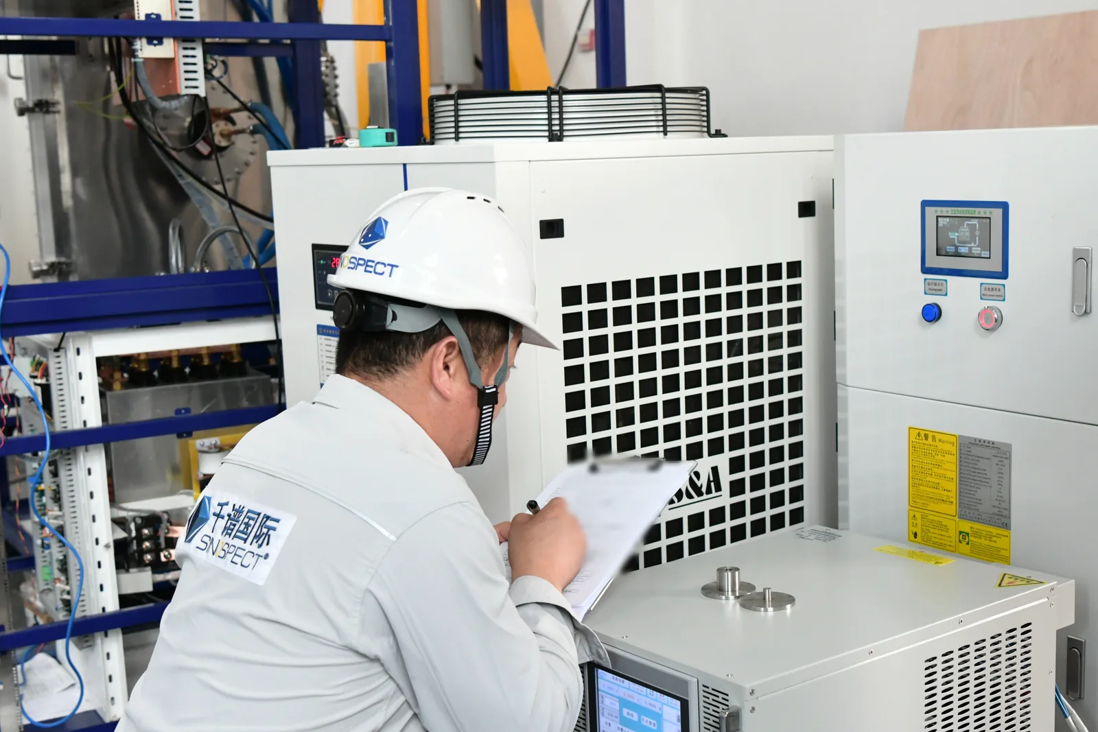 Sinospect QA/QC engineer recording an observed FAT test point beside supplier equipment in China
