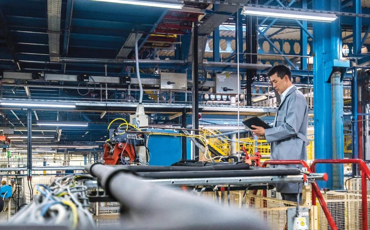 Sinospect industrial inspector reviewing equipment on a factory floor with a tablet