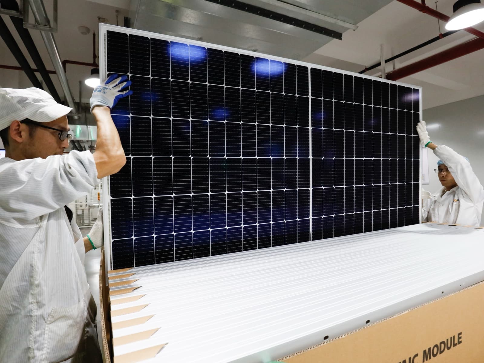Workers inspecting a solar photovoltaic module at a Chinese factory before shipment