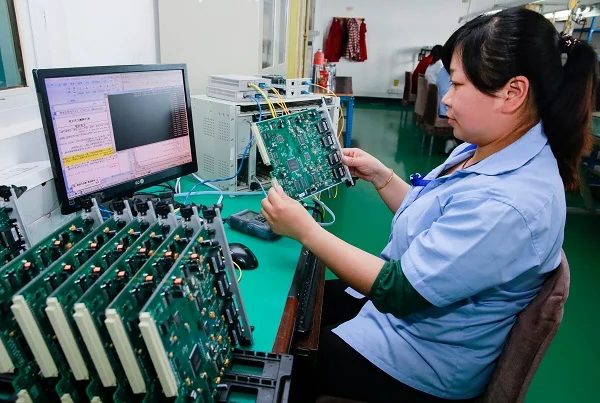 Electronics quality control — technician testing printed circuit boards
