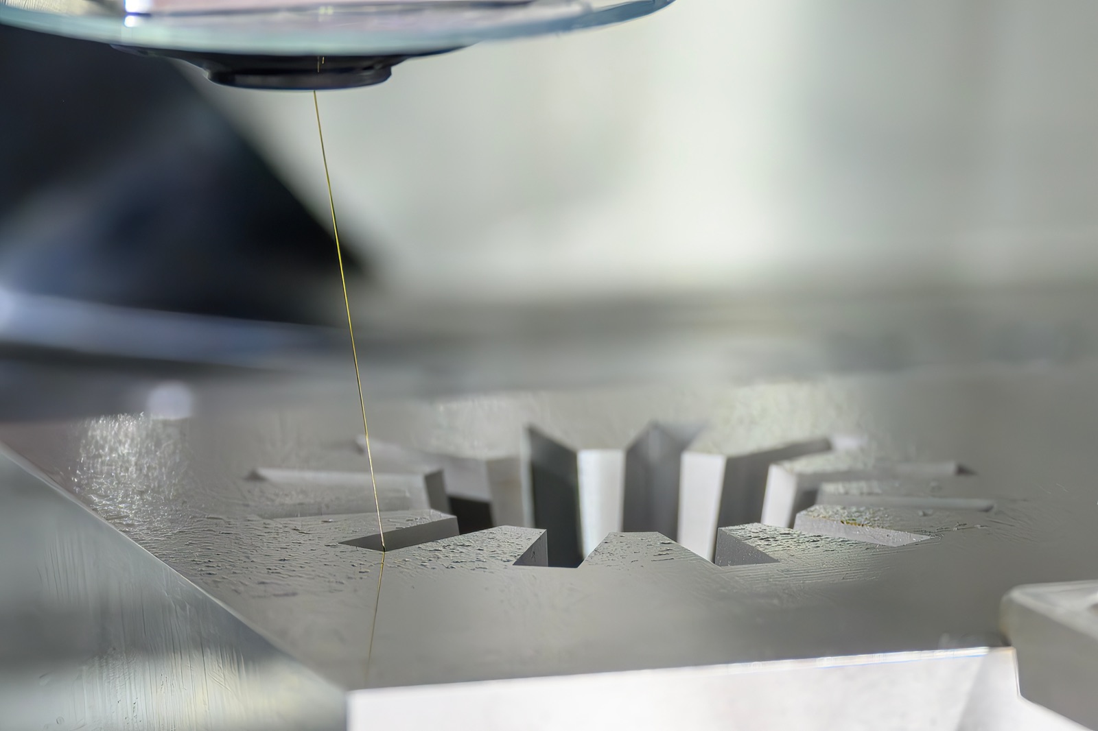 Wire EDM machine cutting a star-shaped mold cavity from hardened steel.